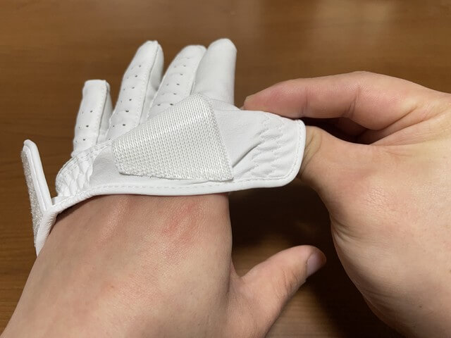 ［ゴルフグローブの外し方］残り4本の指の付け根が出るように裾をまくる