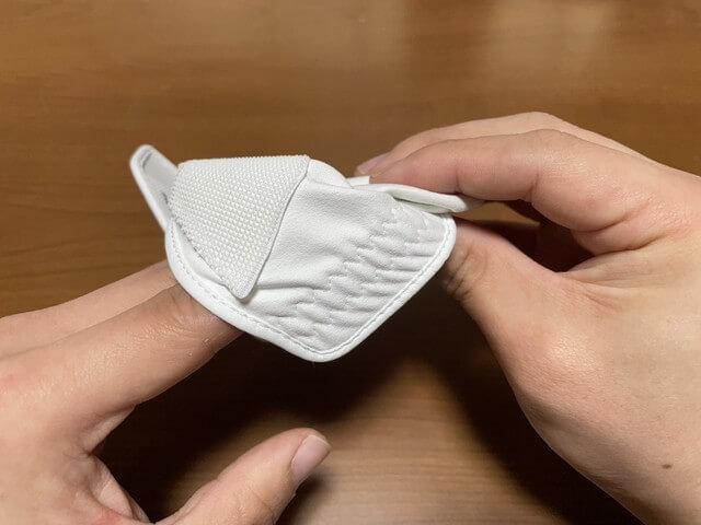 ［ゴルフグローブの外し方］裾と指の先にある生地をつまみながら4本の指を抜く